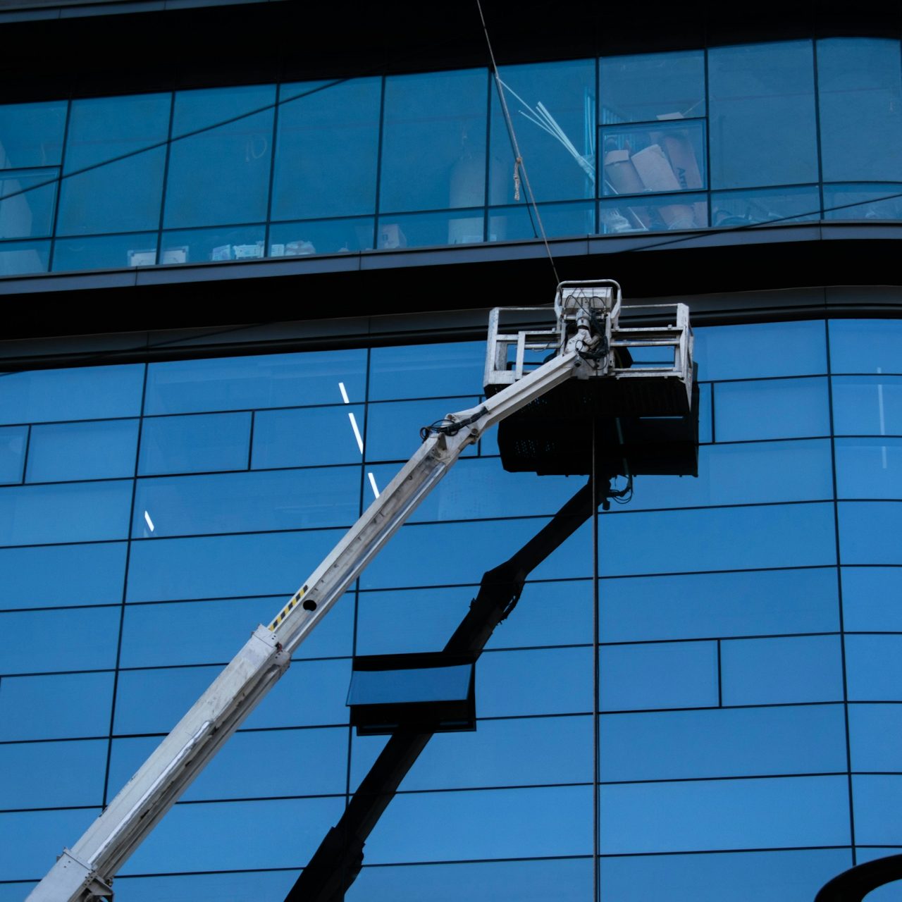 Major Clean Ein Arbeitsbühne reinigt die Glasfassade eines modernen Gebäudes.