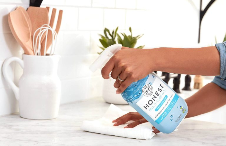 Privat Reinigung Eine Hand hält eine Sprayflasche mit Reinigungsmittel und wischt eine Oberfläche ab.